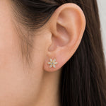 Close-up of an ear wearing a diamond flower earring with a neutral background