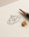 Pencil sketch of a ring on beige paper with gold dust